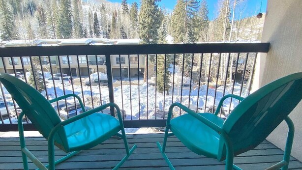 A balcony with two green rocking chairs and a view of a snowy landscape with trees and buildings. - PROMO 5% WEEKLY AND 10% MONTHLY
Fun 2 bedroon/2 bath condo steps from the slopes (Durango)