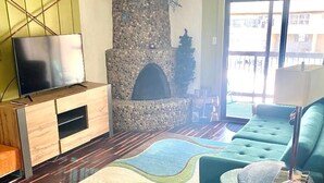A living room with a stone fireplace, a television on a wooden cabinet, a red leather sofa, and a colorful rug. - PROMO 5% WEEKLY AND 10% MONTHLY
Fun 2 bedroon/2 bath condo steps from the slopes (Durango)