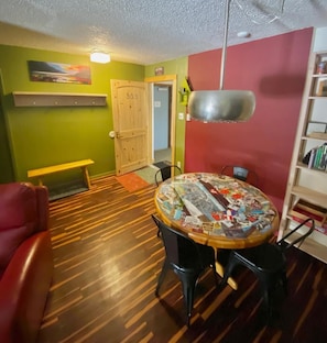 A room with a round table covered in photos, a red couch, a wooden bench, and a bookshelf.
