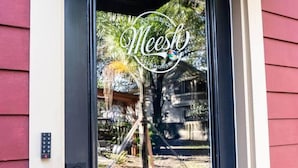 Una puerta con un ventanal que muestra una casa y un árbol.