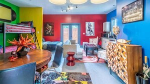 Una habitación colorida con literas, una mesa de comedor y una zona de cocina.