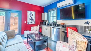 Un espacio habitable compacto con kitchenette, un sofá, una mesa de centro y una decoración en tonos rojo y azul.