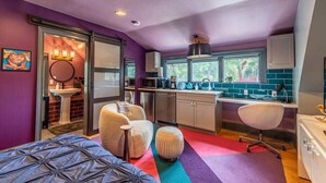 Quarto compacto com cama, um pequeno espaço para sentar e uma cozinha compacta.