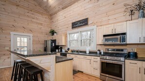 Une cuisine moderne avec des meubles en bois, une cuisinière en acier inoxydable et un coin bar avec des tabourets.