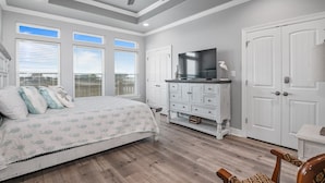 A bedroom with a bed, a dresser, a television, and a ceiling fan.