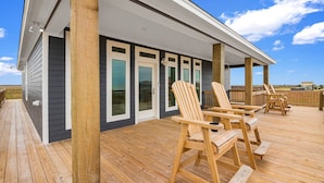 A wooden deck with outdoor seating and a covered area with windows.