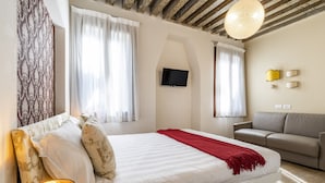 A bedroom with a bed, a sofa, a TV, and a lamp. - Ca' dell'Arciere - Superior Apartment in the Heart of Venice (Venezia)