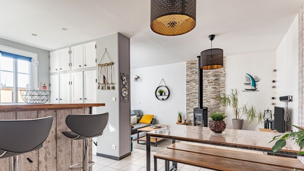 Una cocina moderna con barra, armarios blancos y una pared de acento de piedra.