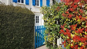 Una casa de dos pisos con contraventanas azules y fachada blanca.