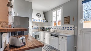 Una cocina con armarios blancos, encimera de madera, un tostador, un fregadero y una ventana con vistas a árboles.