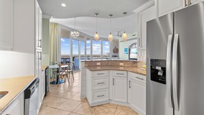 A modern kitchen with white cabinets, a stainless steel refrigerator, and pendant lighting. - Lagoon Front corner unit with lagoon and gulf views! 11th floor 3 bed 3 bath (Gulf Shores)