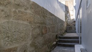 A narrow stone-walled corridor with a staircase leading to a higher level. - Peaceful & Bright Flat with Terrace by Host Wise (Porto)