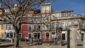 A row of historic buildings with a central tree, a gated entrance, and parked cars. - Peaceful & Bright Flat with Terrace by Host Wise (Porto)