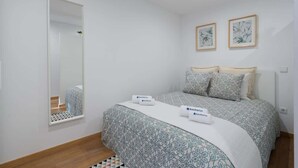 A bedroom with a bed, a mirror, and two framed pictures on the wall. - Peaceful & Bright Flat with Terrace by Host Wise (Porto)