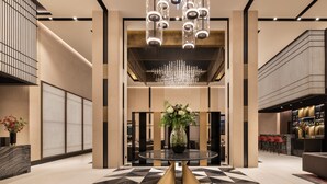 A modern lobby with a round table, a chandelier, and a bar area. - Eurostars Ambassador (Budapest)