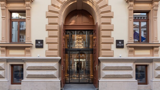 The entrance of the Eurostars Hotel with a grand archway, glass doors, and a chandelier. - Eurostars Ambassador (Budapest)