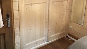A bedroom with wooden wardrobe doors, a bed, and a bedside table. - A bit of Alpine heaven with stunning views! (Les Allues)