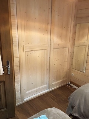 A bedroom with wooden wardrobe doors, a bed, and a bedside table.
