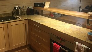 A kitchen with wooden cabinets, a built-in oven, a microwave, and a clock on the wall. - A bit of Alpine heaven with stunning views! (Les Allues)