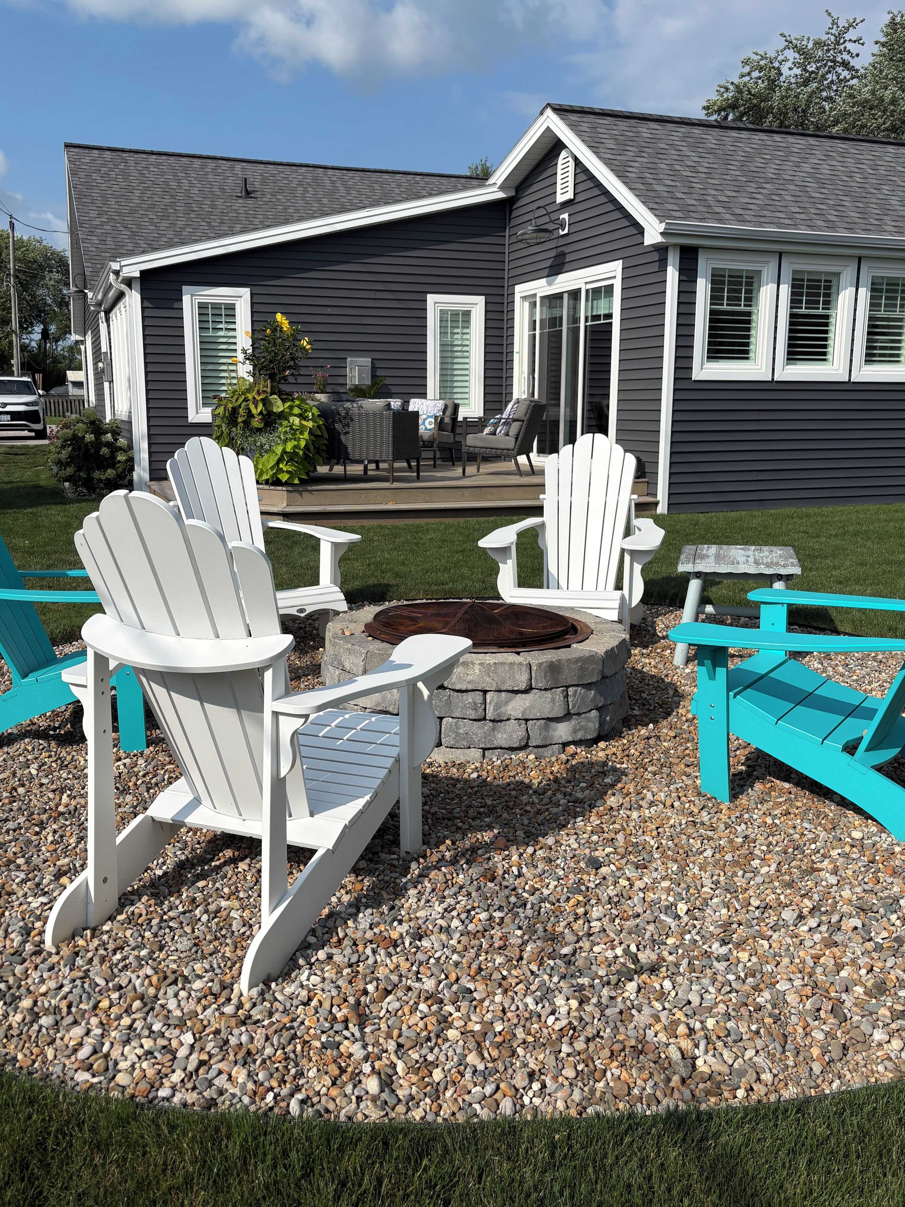 A patio area with Adirondack chairs and a stone fire pit.