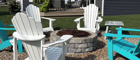 A patio area with Adirondack chairs and a stone fire pit.