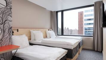A hotel room with two beds, a TV, and a large window with a view of a building.