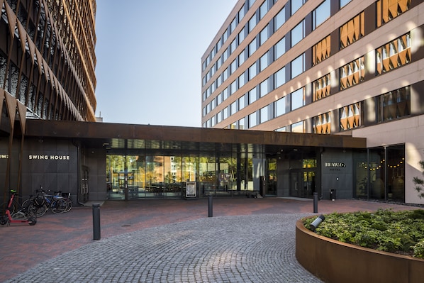 A modern hotel entrance with a brick-paved courtyard, a swing house, and a HYMO hotel sign.