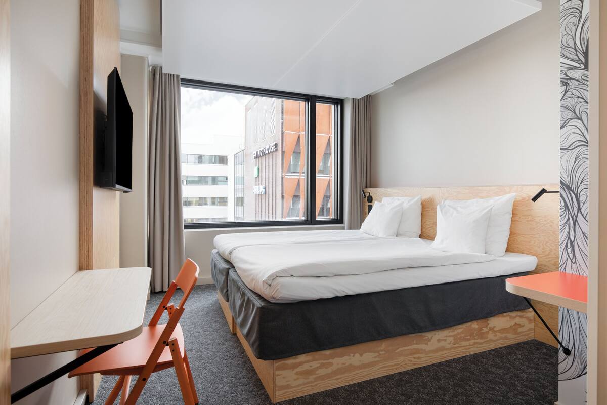 A hotel room with a bed, a desk, and a TV.