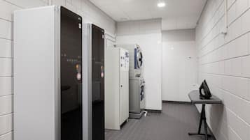 A clean, modern bathroom with a white tiled wall, a grey floor, and a small table with a bag on it.
