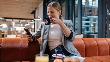 Henkilö istuu nahkasohvalla modernissa sisätilassa, ja hänen edessään on pöytä.