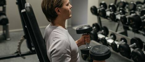 Un gimnasio con una persona usando mancuernas.