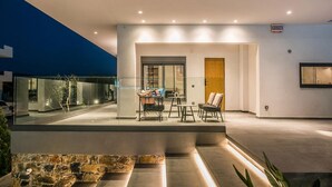 A modern outdoor patio with a glass enclosure, stone seating, and a minimalist design. - Villa Amo With Private Pool (Malevizi)