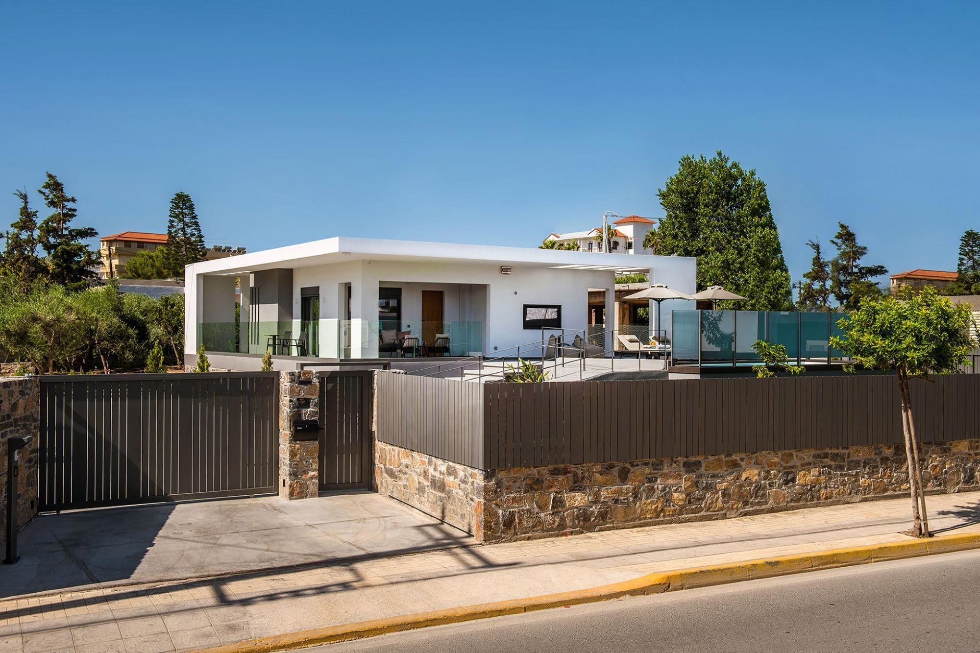 Een modern huis met twee verdiepingen, een overdekte patio en een stenen muur.