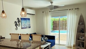 A modern kitchen with a central island, pendant lights, and a view of a pool through the sliding glass door. - Exclusive Beach and Golf Villa with private Hot tub (Puerto Plata)
