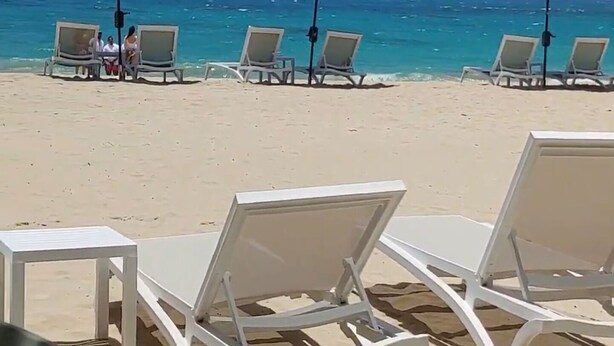 A beach with white lounge chairs and green umbrellas. - Exclusive Beach and Golf Villa with private Hot tub (Puerto Plata)
