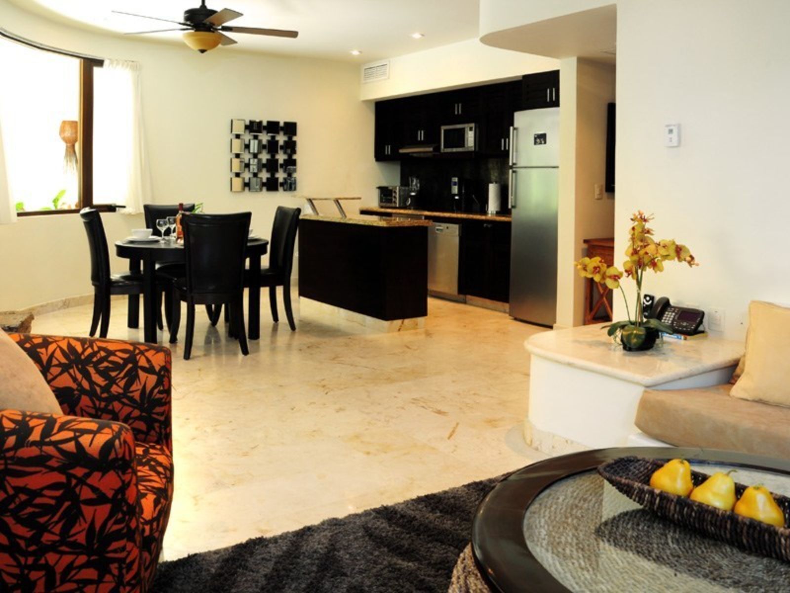 A modern living room with a dining area, kitchen, and a small office space.