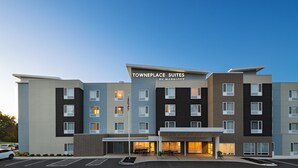 Un hotel de varios pisos con un diseño moderno, que presenta una entrada destacada con zona cubierta y un letrero que dice "Towneplace Suites by Marriott".