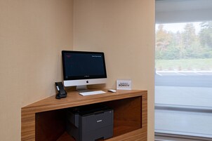Un escritorio con un monitor Apple, teclado, ratón e impresora Brother. Un cartel indica "Marriott Bonvoy".