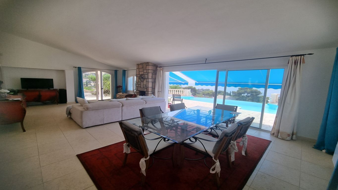 Uma sala de estar ampla com uma mesa de jantar de vidro, um conjunto de sofás e uma televisão.