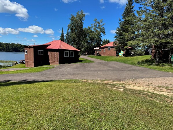 A campground with two wooden cabins, a picnic table, and a lake in the background. - Cozy cabin on Island Lake (Winter)
