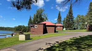 A campground with two wooden cabins, a picnic table, and a small shed. - Cozy cabin on Island Lake (Winter)
