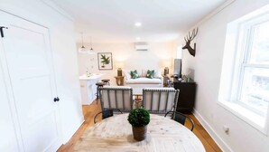 Een gezellige kamer met een ronde houten eettafel, een bed met hoofdbord, en een opgehangen hertenkop aan de muur.