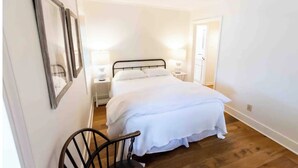 Een slaapkamer met een bed, twee nachtkastjes en een stoel.