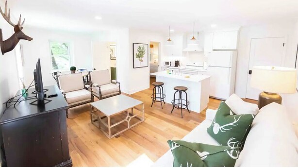 Een moderne woonkamer met een open haard, een bank, een salontafel en een keuken met barkrukken.