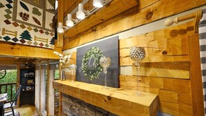 A cozy room with a wooden ceiling, a fireplace, and a wall decorated with a wreath and crystal glass holders. - Free Dollywood Tix/VIEWS/Couples Cabin/HotTub/ (Sevierville)