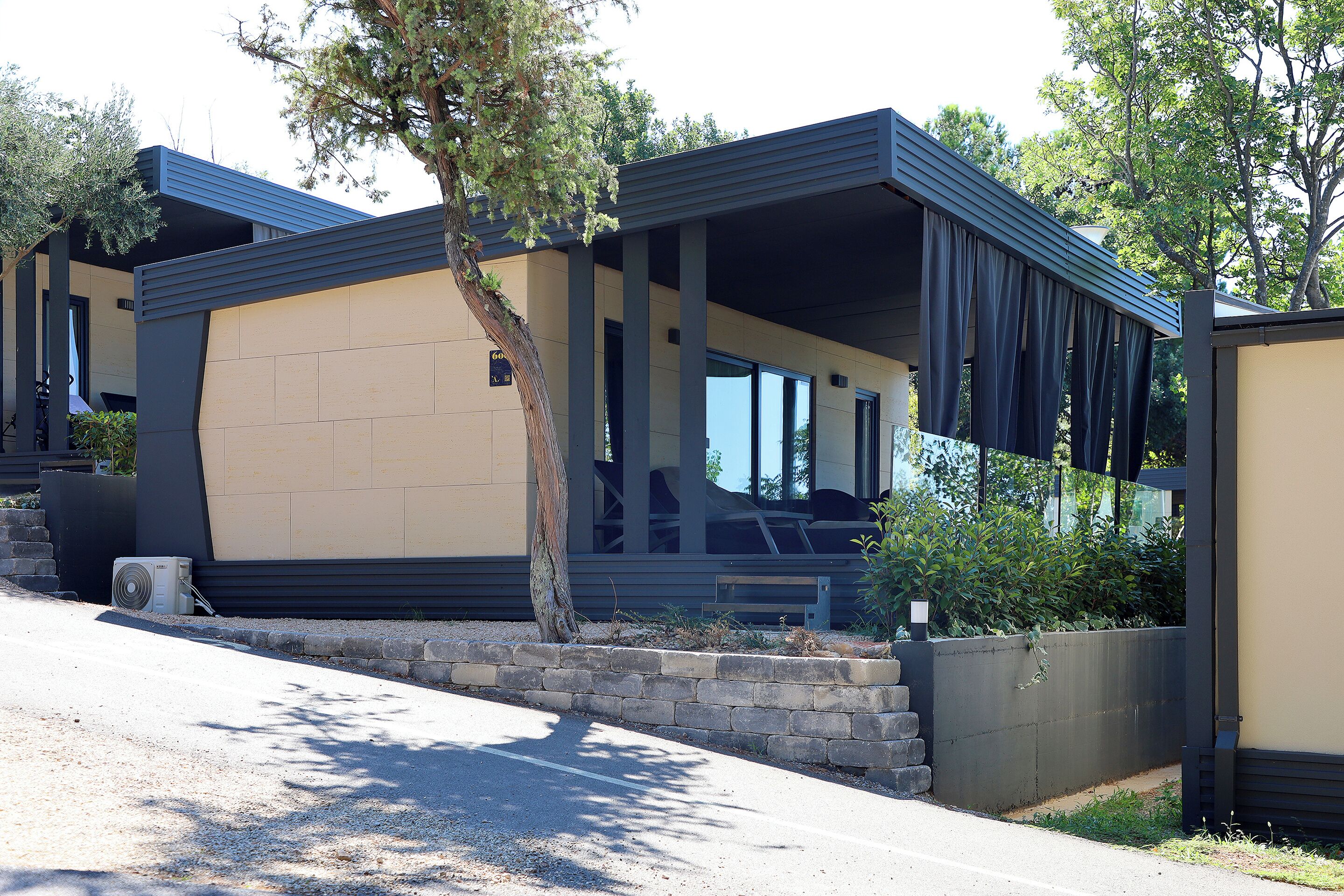 A modern building with a flat roof, large windows, and a covered outdoor area.