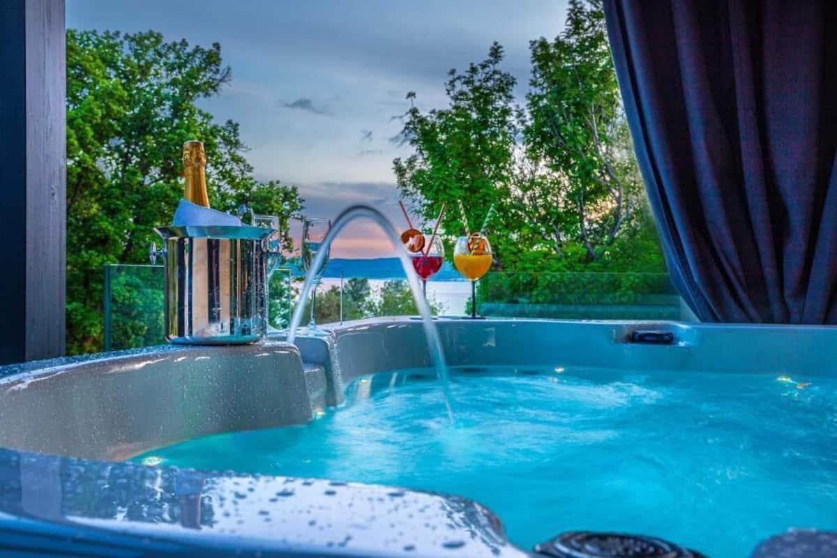 A hot tub with a champagne bottle and two drinks on the side.