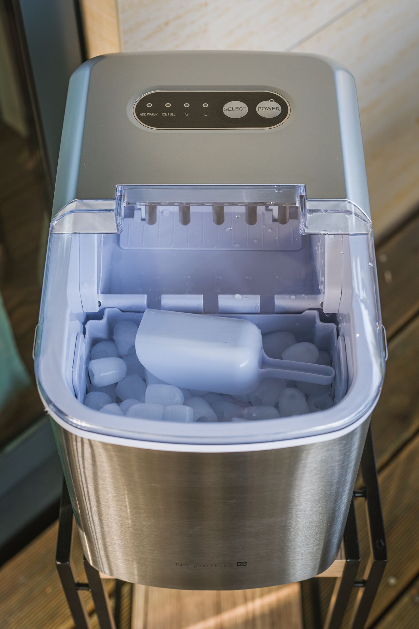 A portable ice maker with a stainless steel container and a control panel with buttons labeled "ADD WATER," "ICE FULL," "SELECT," and "POWER."
