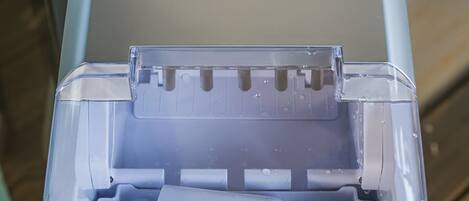 A portable ice maker with a stainless steel container and a control panel with buttons labeled "ADD WATER," "ICE FULL," "SELECT," and "POWER."
