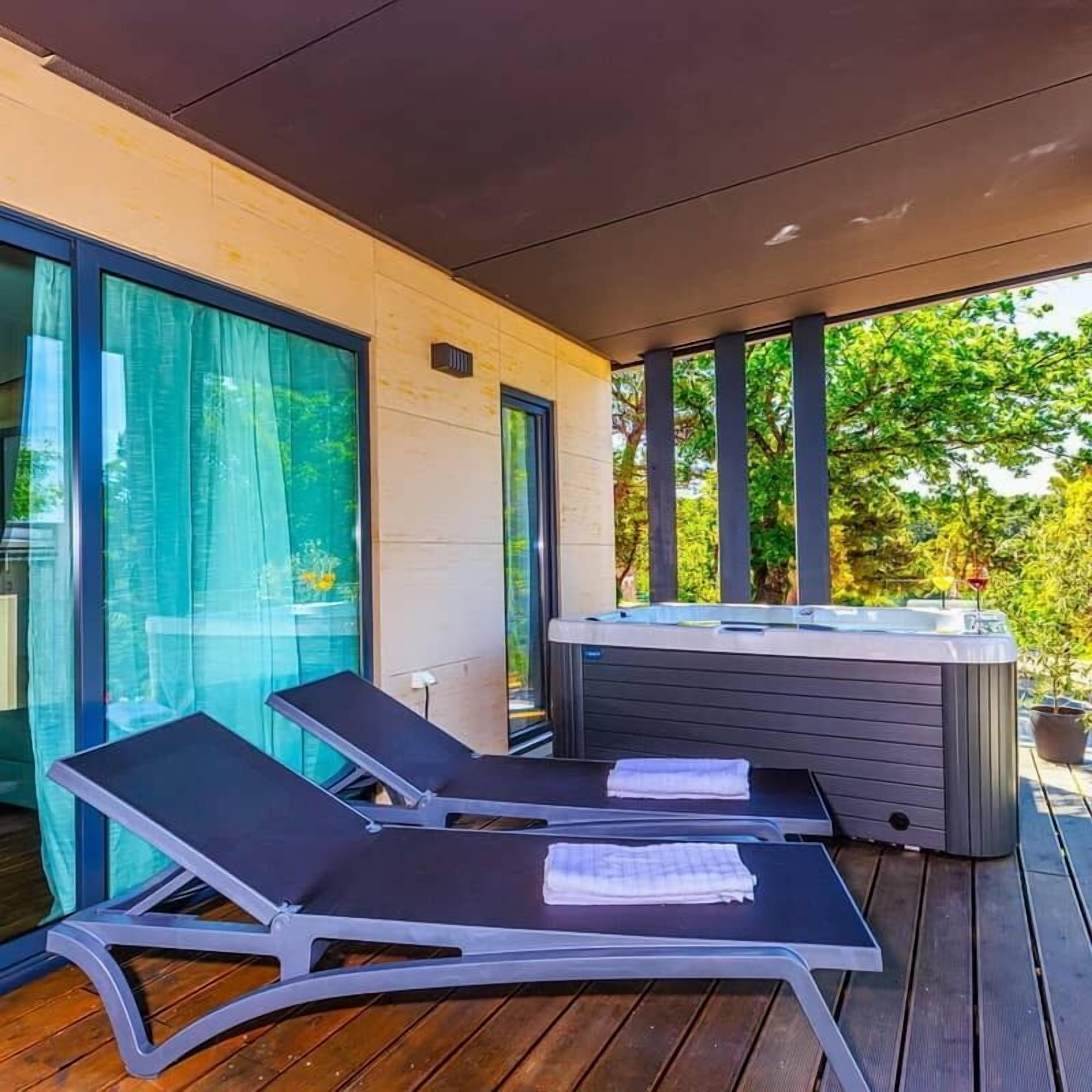 Un patio moderno al aire libre con dos sillones de descanso y un jacuzzi.